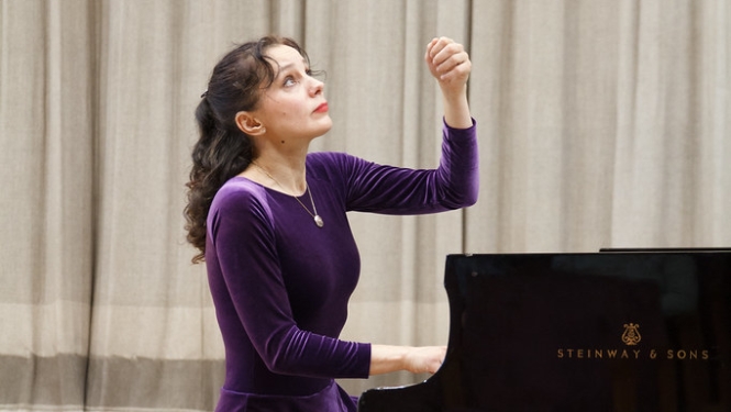Pianiste purpura kleitā spēlē uz Steinway & sons flīģeļa