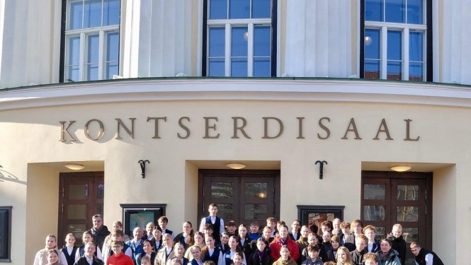 Pūtēju orķestris pozē priekšā koncertzāles uzrakstam Kontserdisaa