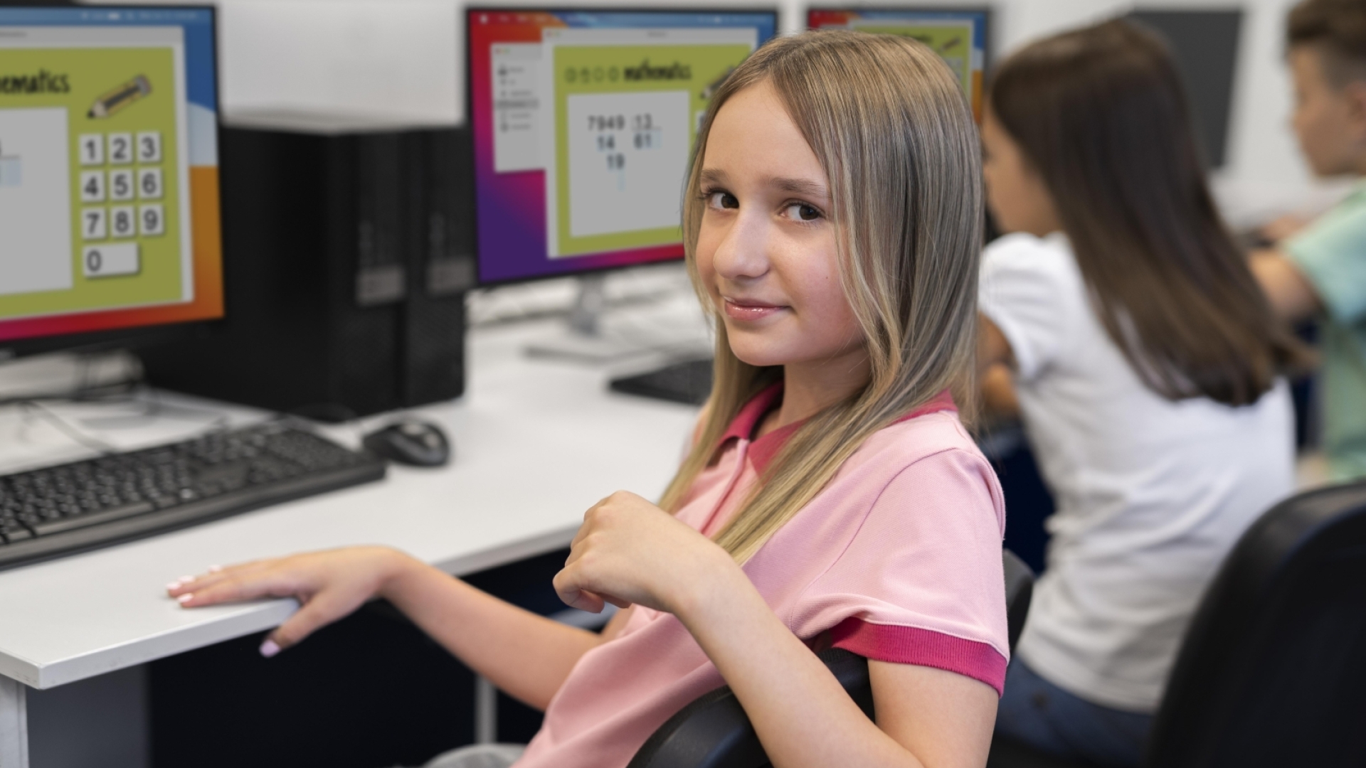 Meitene sēž pie datora datorgrafikas klasē